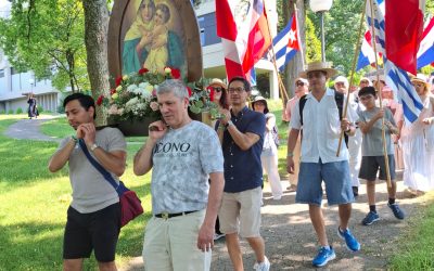 grupo de personas en procesión cargando una imagen de María y banderas de diferentes paises
